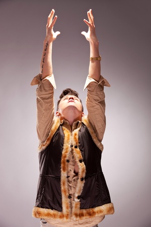 fashion man reaching out for the light on gray backgroundの写真素材