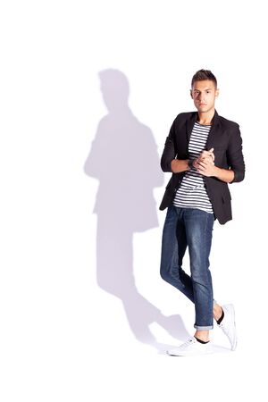 fashion picture of a young handsome man holding his palms together on white background with hard shadowの写真素材