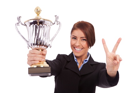 business woman holding a trophy and making victory gesture on white backgroundの写真素材