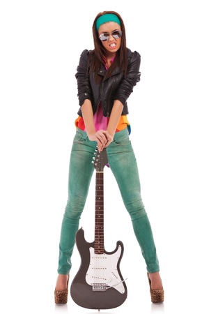 hot rock and roll woman wearing high heels shoes and sunglasses screaming while holding her electric guitar on the ground, on white backgroundの写真素材
