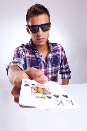Portrait of young man showing poker pair of king and ace of clubs on gray background の写真素材