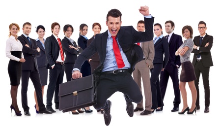 business man holding briefcase jumping with his business team formed of young businessmen and businesswomen standing over a white backgroundの写真素材