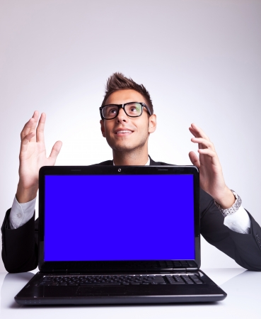 Smiling dreaming young business man looking up to something while working at laptop computer の写真素材