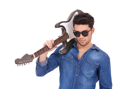 cutout portrait of a casual young man with his electric guitar on his shoulder, looking arrogantly into the cameraの写真素材