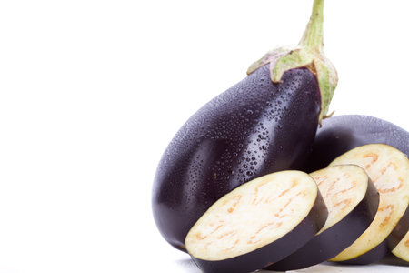 whole and sliced eggplants with water drops on them isolated on white