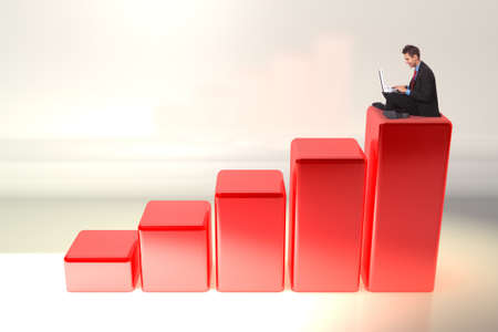young business man working on his laptop computer while sitting on a 3d rising graphの写真素材