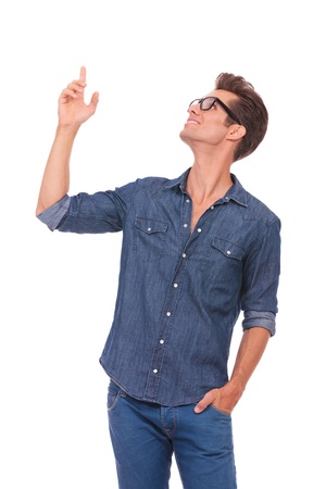 casual young man pointing and looking upwards while holding a hand in his pocket and smiling. isolated on a white background casual young man pointing and looking upwards while holding a hand in his pocket and smiling. isolated on a white background