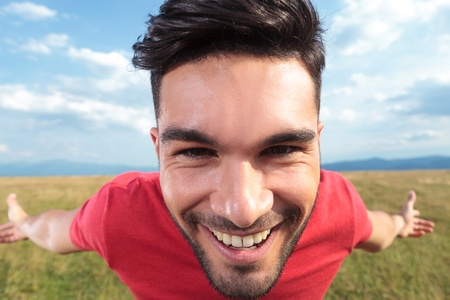 closeup of a casual young man outdoor with his arms wide open is smiling for the cameraの写真素材