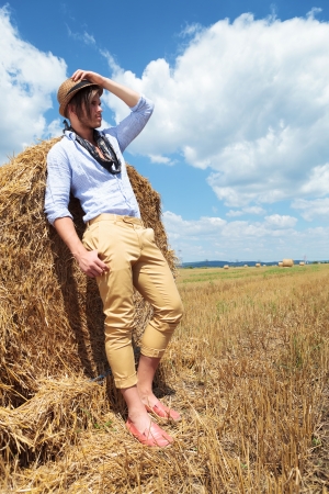 young casual man posing outdoor, leaning on a haystack の写真素材