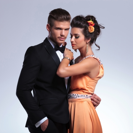 young fashion couple embracing while man looks at the camera with a hand in his pocket. on gray backgroundの写真素材