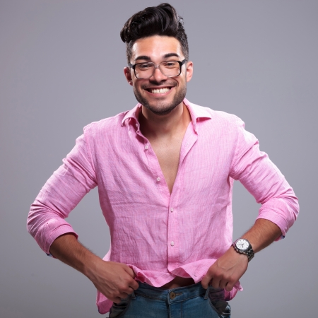 young fashion man pulling his pants up with a silly smile on his face. on a gray backgroundの写真素材