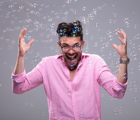 young fashion man going crazy while bubbles fly around him. on a white backgroundの写真素材