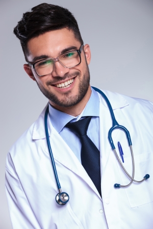 closeup portrait of a young male doctor smiling for the camera. on gray backgroundの写真素材