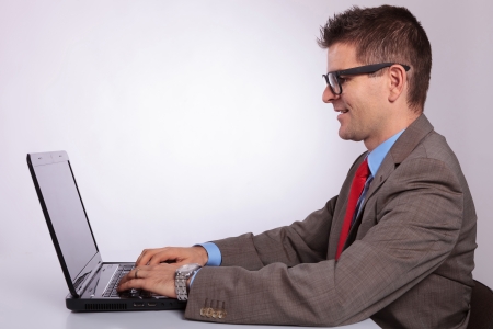 side view picture of a young business man working on his laptop . on a gray backgroundの写真素材
