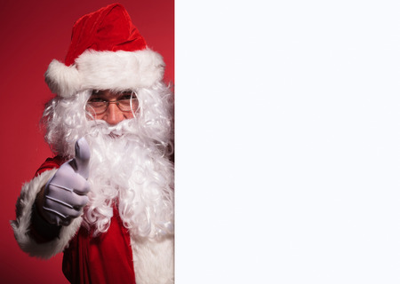 santa claus is presenting a blank board and makes the thumbs up ok hand signの写真素材