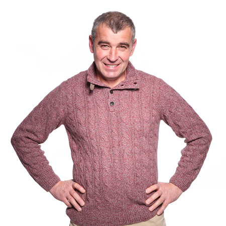 happy casual old man in warm sweater smiling to the camera with hands on hipsの写真素材