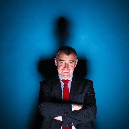 dramatic picture of a senior business man smiling on a blue background with hard shadowの写真素材