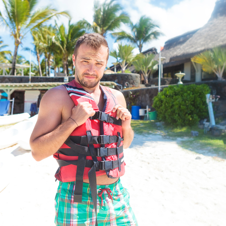 man preparing with life vest to go on the sea and have some fun in the wavesの写真素材