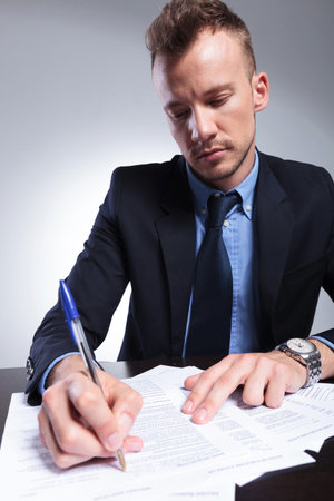 young business man writing something on a form. on a light gray studio backgroundの写真素材