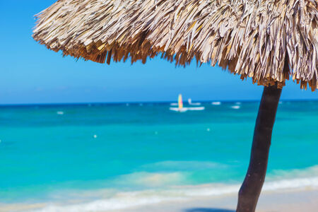 straw umbrella closeup on a beautiful tropical beach, with little boat の写真素材