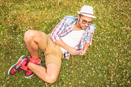 casual man lying down to his side and looks away, on a fieldの写真素材