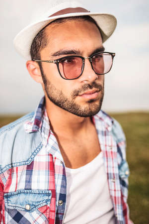 side view of a young casual man with glasses and hat looking away from the cameraの写真素材