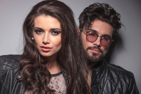 Beautiful fashion woman posing for the camera while her lover is leaning on a grey wall behind her.の写真素材