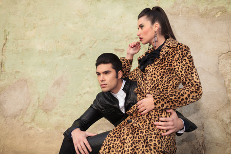 Beautiful fashion woman sitting on her boyfriend's lap while looking away from the camera.の写真素材