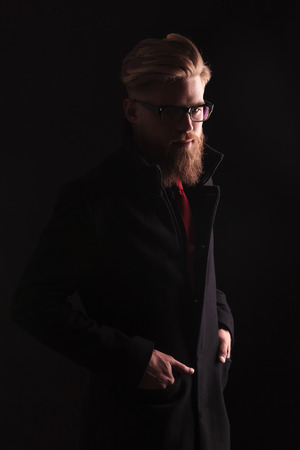 Dark background image of a elegant business looking down while holding both hands in pockets.の写真素材