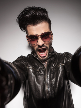 Close up picture of a casual fashion man shouting while holding the camera.の写真素材