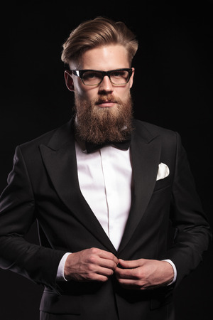 Elegant young business man looking at the camera while closing his jacket.の写真素材