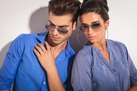 Close up picture of a casual fashion couple looking down, on studio background.の写真素材