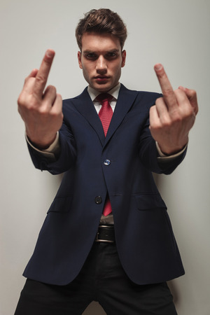 Serious young business man showing the fuck you gesture with both hands.の写真素材