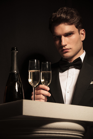 Picture of a elegant young business man holding a glass of champagne while looking at the camera.の写真素材