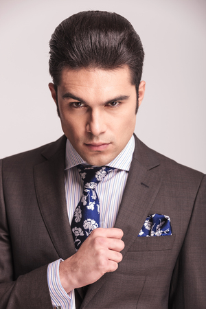 Close up picture of a young handsome business man looking at the camera while fixing his collar.の写真素材