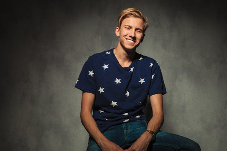 blond sexy casual man is laughing while sitting in studio