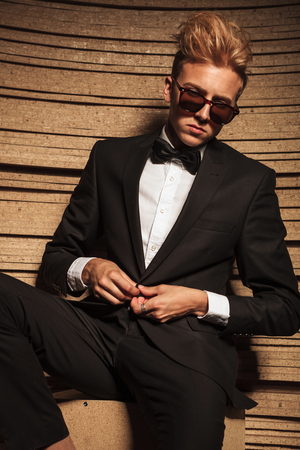 Blond young business man closing his jacket while looking down.の写真素材