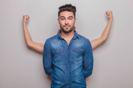 Young woman standing behind her lover, showing her muscles while he is looking at the camera.の写真素材
