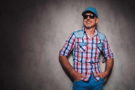 smiling senior casual man wearing baseball hat looking away to side in studioの写真素材