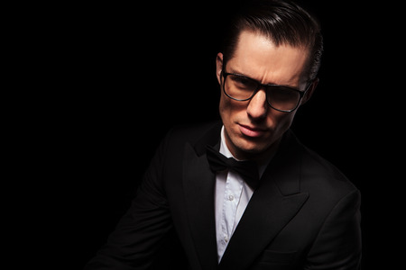 dark portrait of attractive businessman wearing glasses posing in studio background looking at the cameraの写真素材