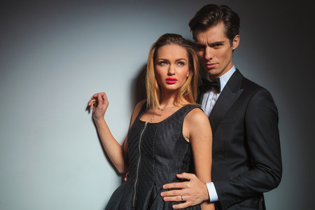 elegant businessman in black suit looking at the camera while embracing woman from behind.の写真素材