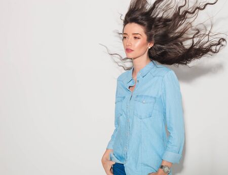 side view of a young attractive woman with fluttering hair looking away from the cameraの写真素材