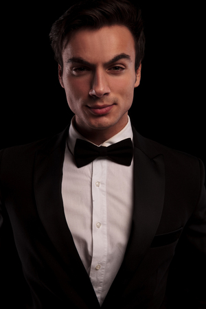 serious sexy man in tuxedo posing for the camera on black studio backgroundの写真素材