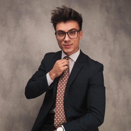 young happy business man fixing his tie , studio pictureの写真素材