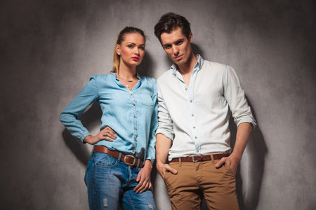 beautiful casual couple standing together in studio and look at the cameraの写真素材