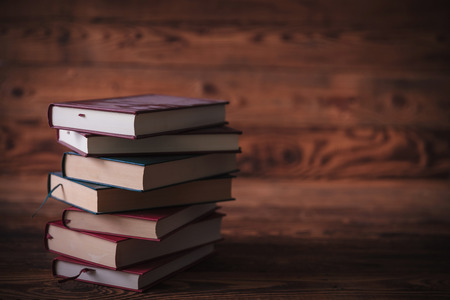 dirty unread old books waiting for a reader on wooden backgroundの写真素材