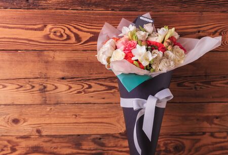 colorful bunch of flowers in a cone with copyspace on old wooden backgroundの写真素材