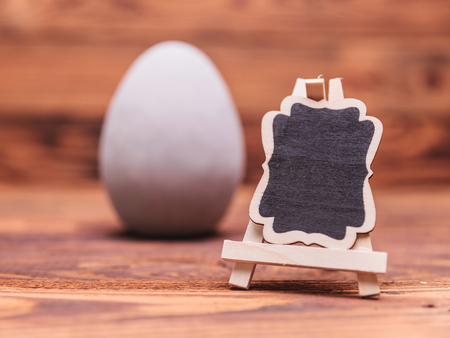 blank board in front of an easter egg on odl wood backgroundの写真素材