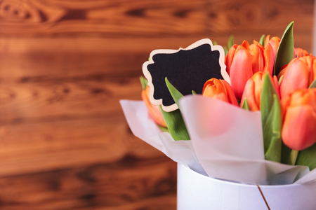 box of orange tulips with a card for copyspace on wooden backgroundの写真素材