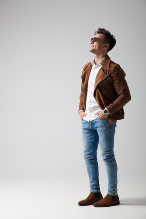 side view of a casual man looking up at something on grey backgroundの写真素材